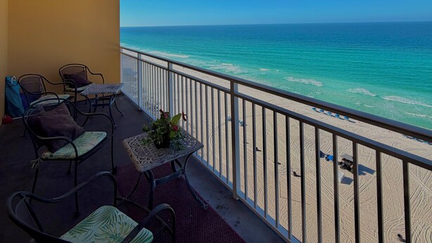 Een balkon met uitzicht op de oceaan, voorzien van stoelen en een tafel.