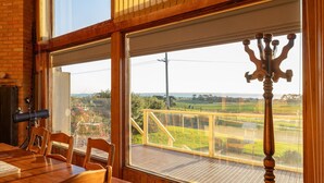 Comedor con mesa y sillas, ventanas amplias con vistas al campo y un telescopio a la izquierda.