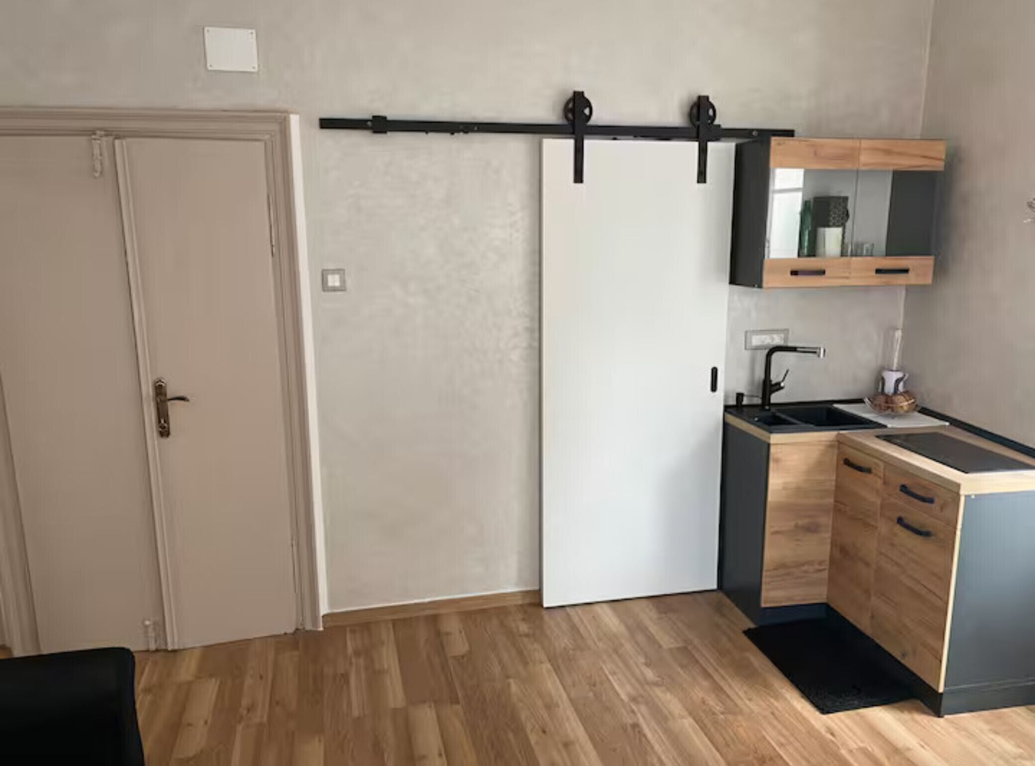 A compact kitchen with a sliding door, a small sink, and a wooden countertop.