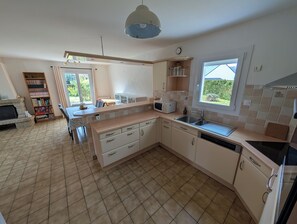 Eine moderne Küche mit Kochinsel, integriertem Mikrowellenherd und Blick auf Grünflächen.