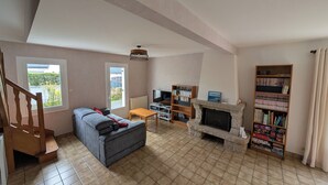 Ein Wohnzimmer mit einer Couch, einem Kamin, einem Fernseher und einem Bücherregal.
