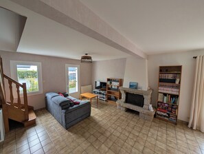 Ein Wohnzimmer mit einer Couch, einem Kamin, einem Fernseher und einem Bücherregal.