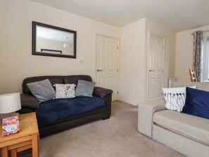 Ein Wohnzimmer mit einem dunkelbraunen Sofa, einem beigen Sofa, einem Holztisch und einem Spiegel an der Wand.