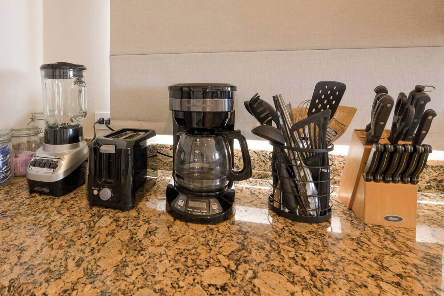 Un plan de travail de cuisine avec un mixeur, un grille-pain, une machine à café et un bloc à couteaux.