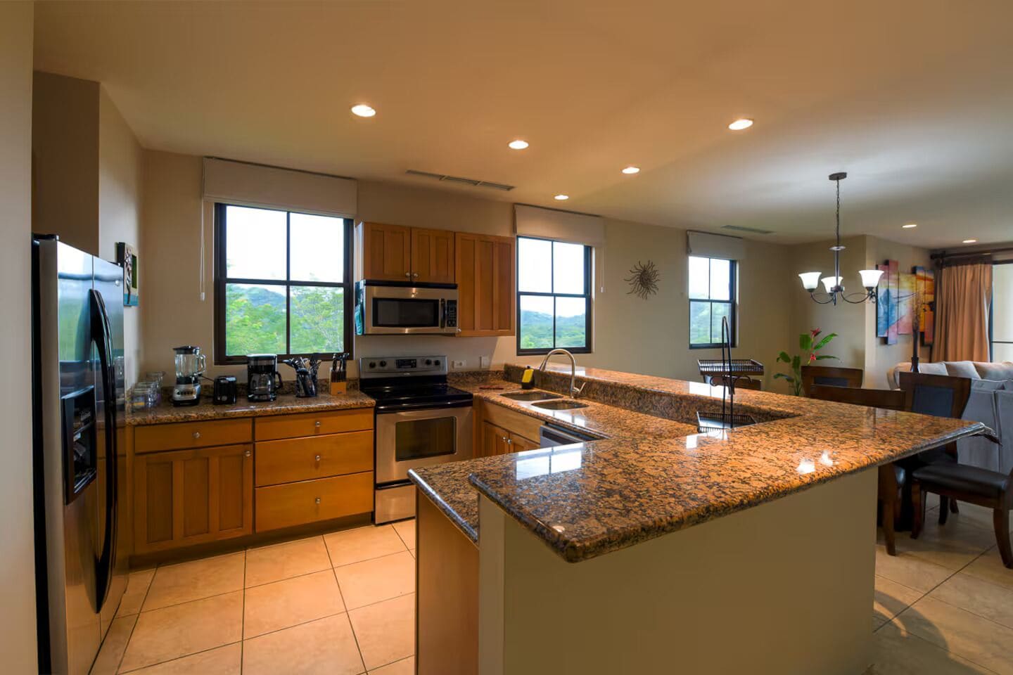 Una cocina moderna con encimeras de granito, electrodomésticos de acero inoxidable y ventanas amplias.