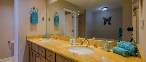 A bathroom with two sinks, a large mirror, and a butterfly decoration.