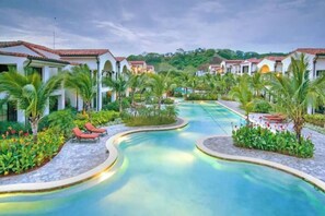 A resort with a swimming pool, palm trees, and white buildings with red roofs. - Stunning Oceanview Condo w/ Exceptional Views & Resort-Style Amenities (Coco)