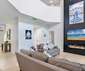 Ein modernes Wohnzimmer mit grauem Sofa, Kamin und Bildern an der Wand.