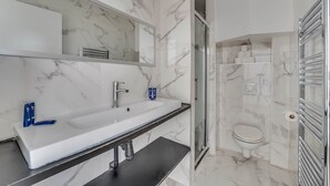 Ein modernes Badezimmer mit Marmorwaschtisch, Spiegel, Dusche und Toilette.