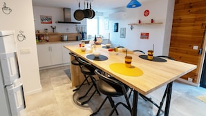 Una cocina moderna con una mesa de madera, sillas negras y un colgador para ollas.