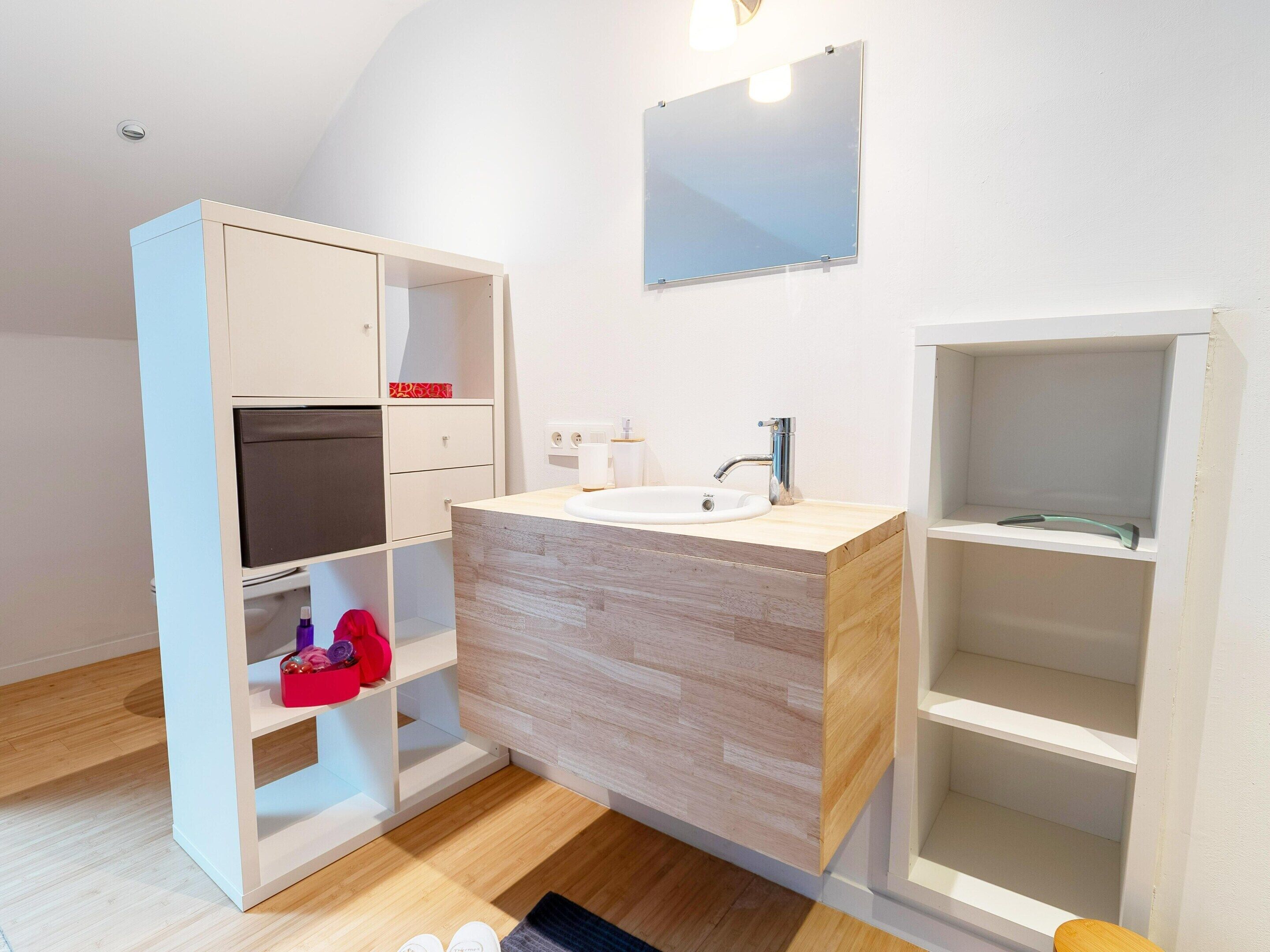 Et moderne badeværelse med en trækommode, et spejl og indbyggede hylder.