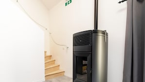Una habitación de esquina con un radiador negro, una escalera y una puerta con letrero de salida.