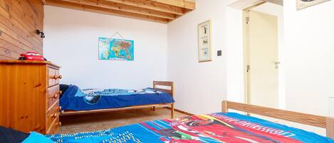 Een slaapkamer met een bed, een houten dressoir en een wereldkaart aan de muur.