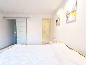 A modern bedroom with a bed, a walk-in closet, a shower, and a painting on the wall. - Apres la Rando: Ardennes Family Nature Cottage for 6 (Comblain-au-Pont)