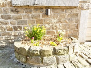 Una jardinera de piedra con flores frente a un muro de piedra.