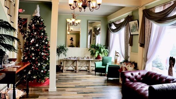 Una habitación con un árbol de Navidad, una araña, una mesa de comedor y un sofá de cuero.