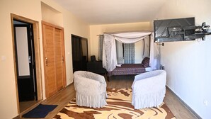 A bedroom with a canopy bed, a TV mounted on the wall, and a large rug. - la villa du parc (Niaga)
