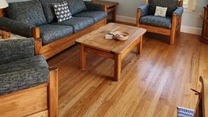 A living room with a sofa, armchair, coffee table, and a lamp. - Charming 2-bedroom house in peaceful Ogunquit with AC and screened porch. (Ogunquit)
