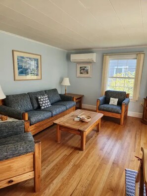Ein Wohnzimmer mit Sofa, Sessel, Couchtisch und Lampe.