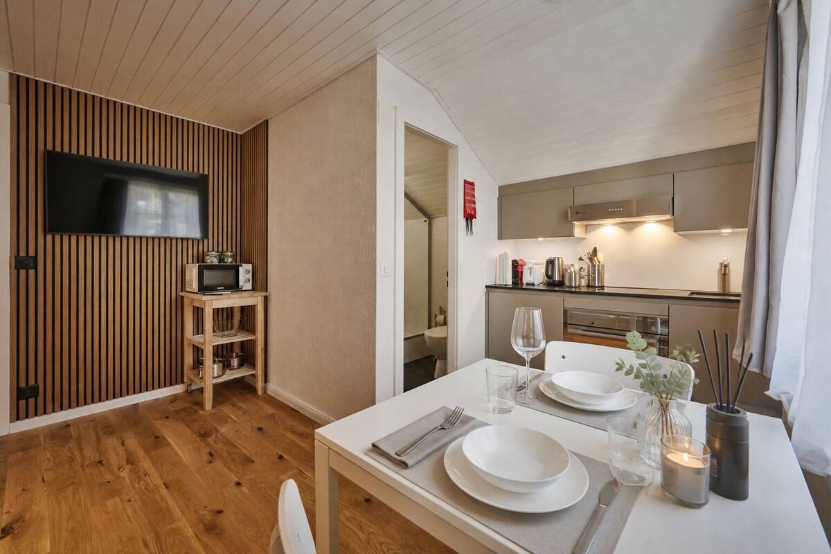A modern kitchen with wooden paneling, a microwave, and a dining area with a table set for two.