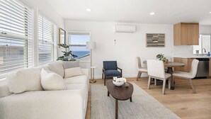 A modern living room with a sofa, dining table, and chairs, a small coffee table, and a view of the ocean. - 2 Bedroom 1 Block From the Sand Manhattan Beach (Manhattan Beach)