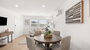 A modern living room with a round dining table, four chairs, a sofa, and a TV mounted on the wall. - 2 Bedroom 1 Block From the Sand Manhattan Beach (Manhattan Beach)