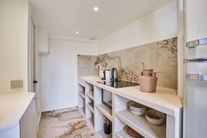 A modern kitchen with white cabinetry, a marble backsplash, and built-in shelves. - Charming AC Duplex - Bastille Le Marais (Paris)