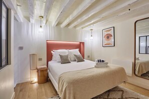 A bedroom with a bed, bedside table, lamp, and a mirror. - Charming AC Duplex - Bastille Le Marais (Paris)
