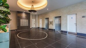 Un hall espacioso con un diseño de suelo circular, una lámpara moderna y un mostrador de recepción con una planta.