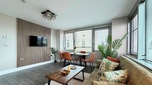 Una sala de estar moderna con sofá, mesa de centro, televisión y comedor.