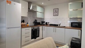 Uma cozinha moderna com armários brancos, forno embutido, micro-ondas e geladeira.