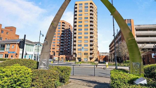 A tall building with multiple floors, surrounded by greenery and a pedestrian pathway. - Thamesview | Heathrow | 2 Bed (Staines-upon-Thames)