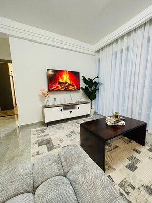 A modern living room with a flat-screen TV, a dark coffee table, a grey sofa, a white cabinet, and a patterned rug. - Cozy 1-bedroom apartment in quaint Nairobi with fitness room near yaya centre (Nairobi)