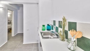 Eine moderne Küche mit Spüle, zwei Glas-Seifenspendern, einem Holzlöffel und einer Vase mit Trockenpflanzen.