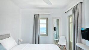 Ein Hotelzimmer mit Bett, Fernseher, Schreibtisch und Meerblick.
