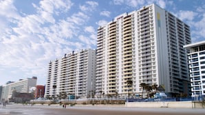 A high-rise hotel with multiple balconies, a beach in the foreground, and palm trees. - Spacious 3-bedroom Wyndham condo on the Atlantic  inDaytona Beach. (Daytona Beach)