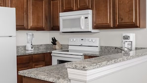 A kitchen with a refrigerator, microwave, stove, and coffee maker. - Spacious 3-bedroom Wyndham condo on the Atlantic  inDaytona Beach. (Daytona Beach)