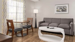 A modern living room with a grey sofa, a round coffee table, a wooden dining table with two chairs, a floor lamp, and a framed picture on the wall. - Spacious 3-bedroom Wyndham condo on the Atlantic  inDaytona Beach. (Daytona Beach)