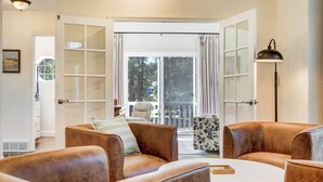A room with a large sliding glass door leading to a balcony, leather sofas, a round coffee table, and a floor lamp. - Ridgemont Hall! Grand Mountain Home w/ Peak Views (Monument)