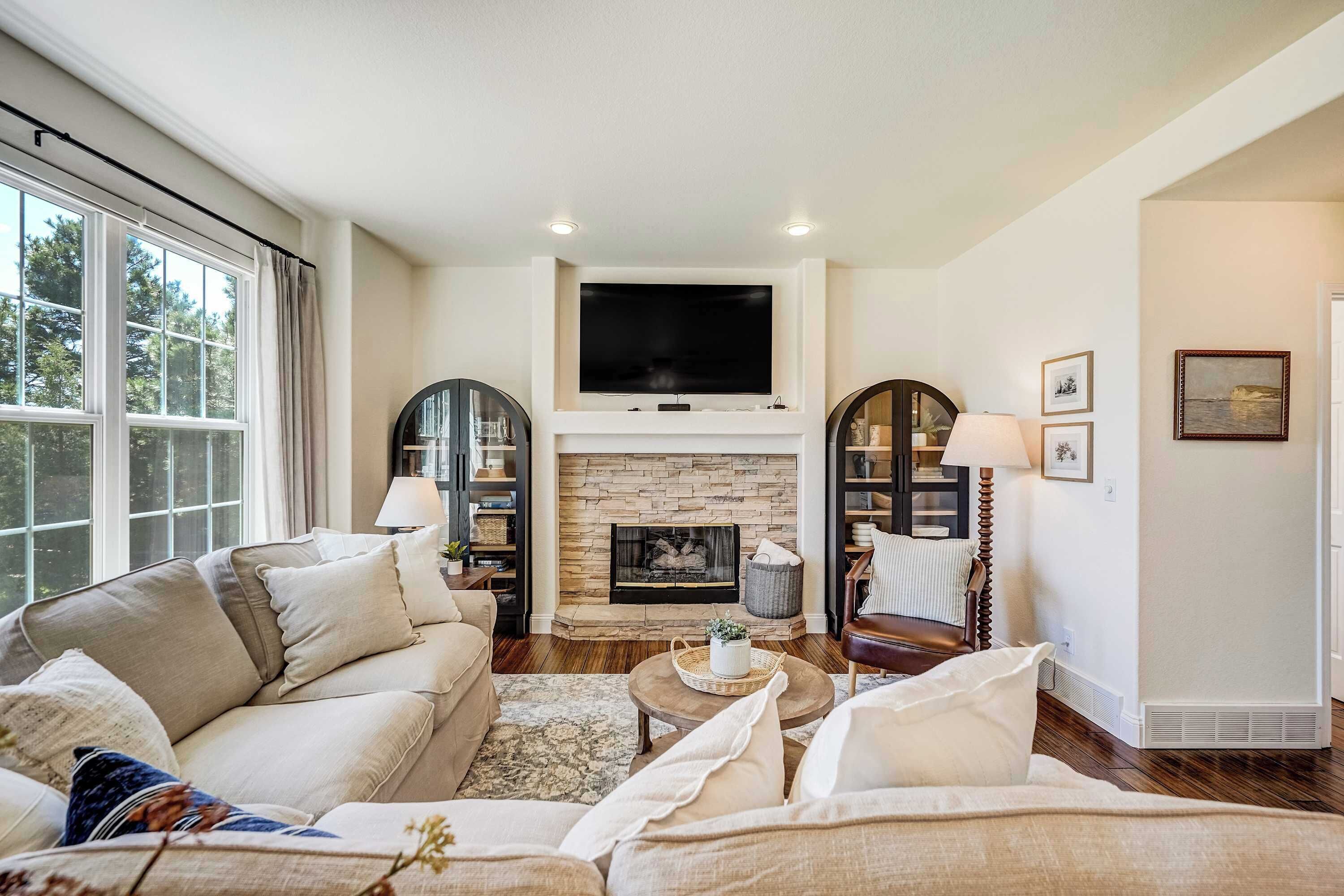 A living room with a fireplace, sofa, coffee table, and a television mounted above the fireplace.