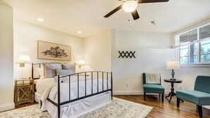 A bedroom with a bed, two chairs, a small table, a ceiling fan, and a window. - Ridgemont Hall! Grand Mountain Home w/ Peak Views (Monument)