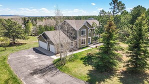 A two-story house with a garage, surrounded by trees and a clear sky. - Ridgemont Hall! Grand Mountain Home w/ Peak Views (Monument)