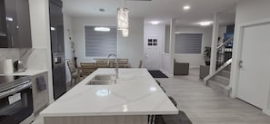 A modern kitchen with a large island, built-in appliances, and a staircase leading to another level. - Vibrant Homestead (Edmonton)