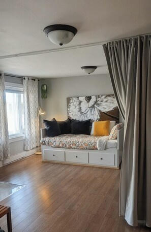 A room with a bed, a window with curtains, a ceiling light, and a wall-mounted plant. - In the heart of old Lévis! Close to the ferry that will take you to Old Quebec! (Lévis)