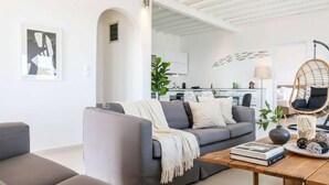 A modern living room with a grey sofa, a wooden coffee table, and a hanging chair. - Kalafatis Stay With Private Pool (Mykonos)