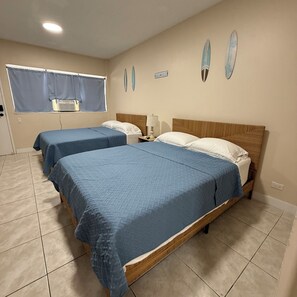 Hotelkamer met twee bedden, een raam met gordijnen, een wandairconditioner en een bordje met de tekst strandhuis.