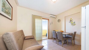 Un salón con sofá, una mesa de comedor y sillas, y una puerta que da a un balcón.
