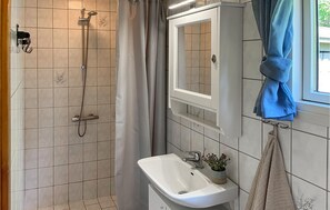 Ein Badezimmer mit Dusche, Waschbecken, Spiegel und Handtuchhalter.