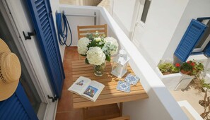 A wooden table with a vase of white flowers, a book, and blue and white tiles. - Lefkes Home With Village Views (Paros)