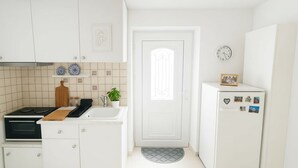A kitchen with white cabinets, a stove, a sink, and a refrigerator.